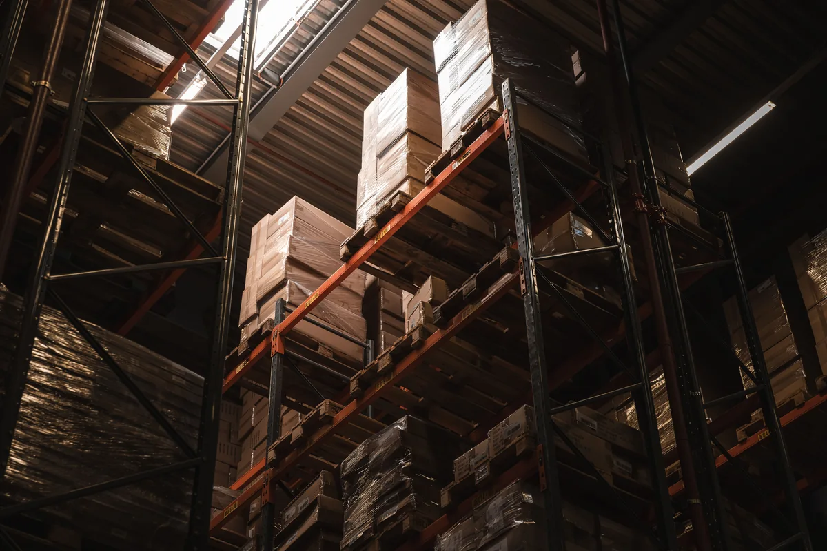 Pallet racks stacked with cardboard boxes inside a warehouse.